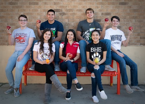 High school students holding fruit in their hands