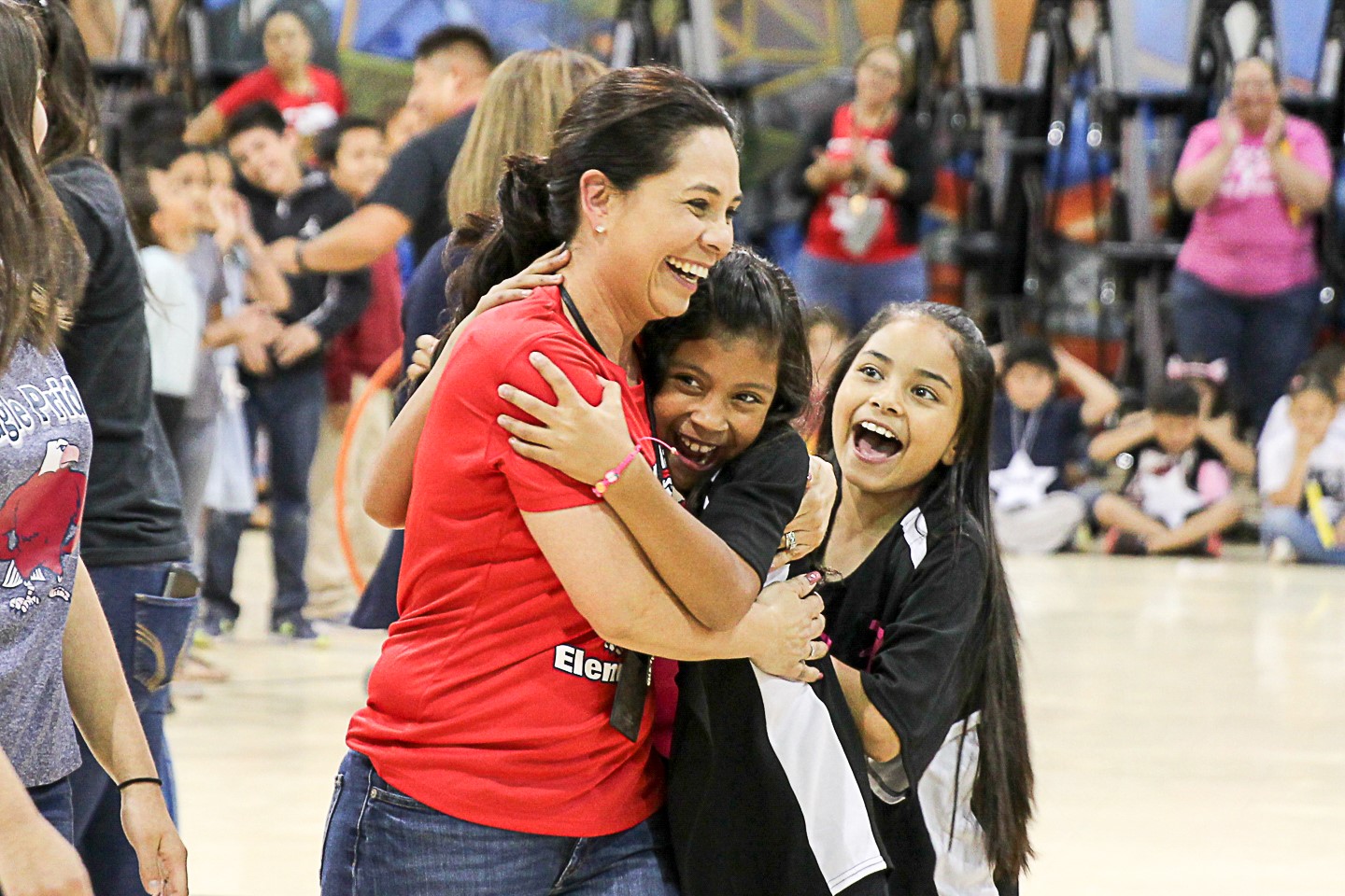 Teacher walking in gym as one girl hugs her